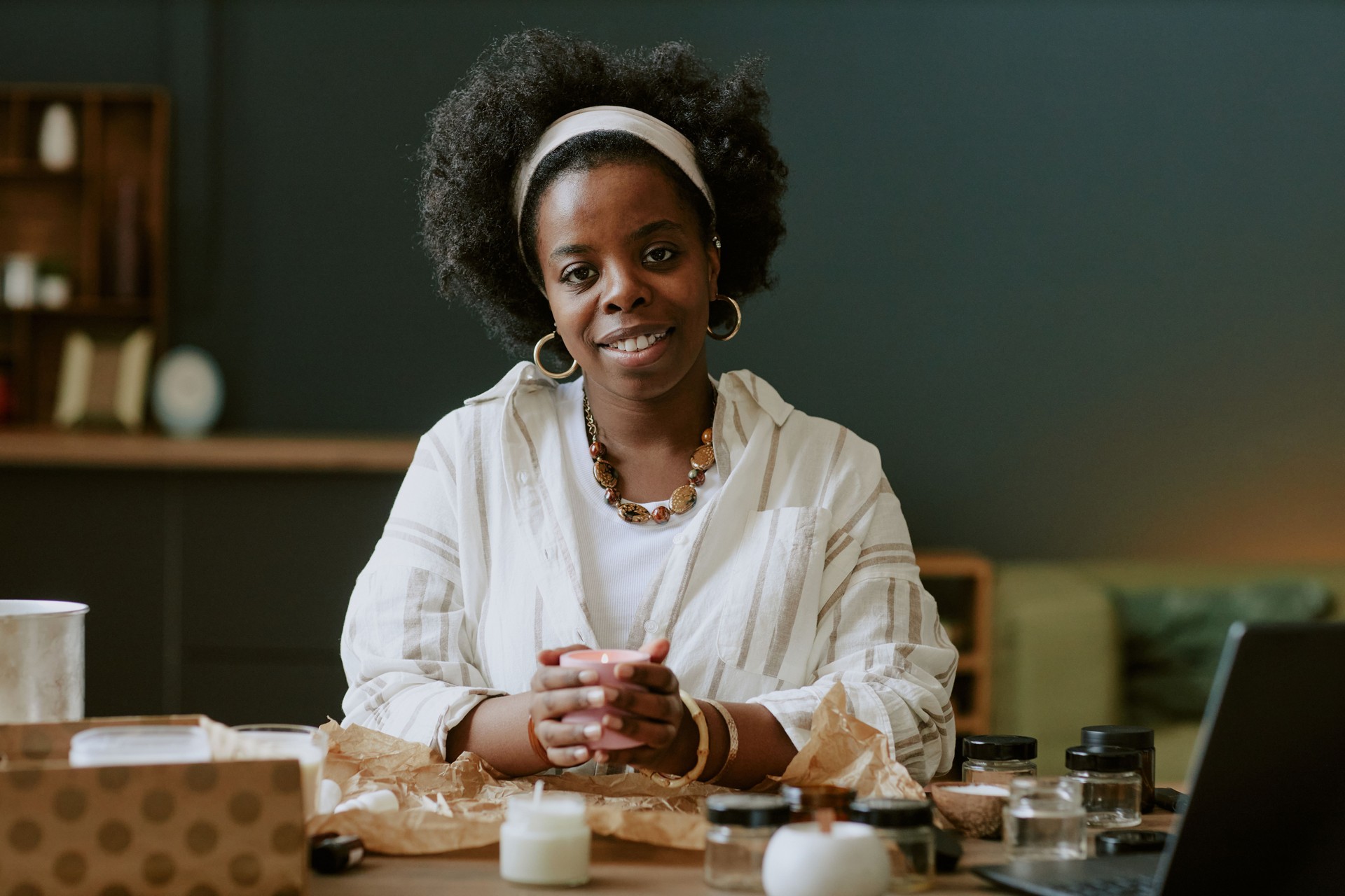 Portrait of Smiling Woman Draping Candles in Cozy Workspace